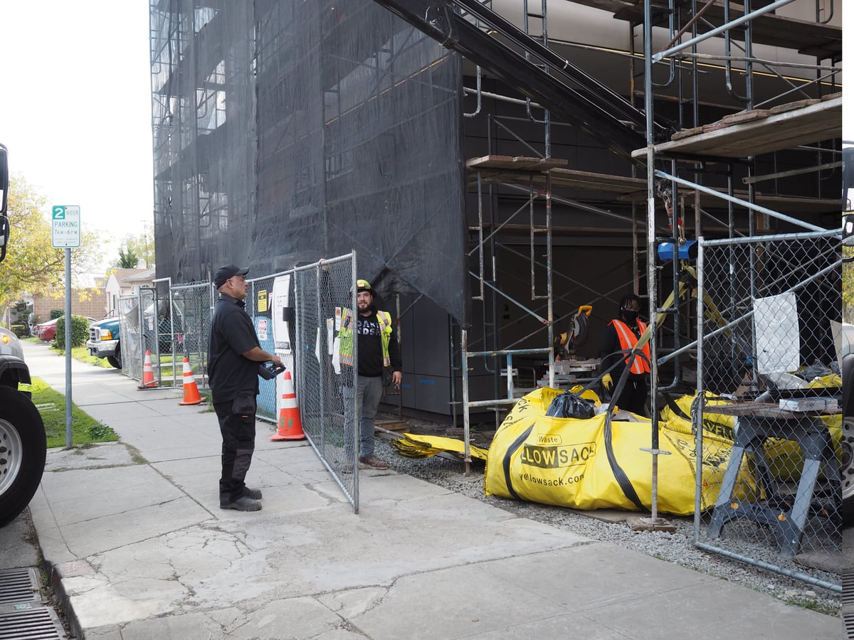 Three Yellowsacks lined up on a construction site with a crew at work