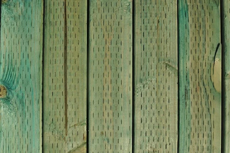 A treated post with incision marks next to bare lumber