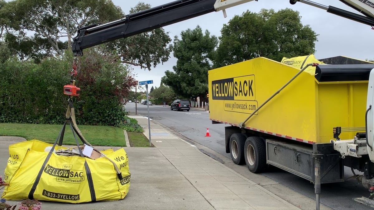 A Yellowsack crane truck lifting a full bag of construction and demolition debris